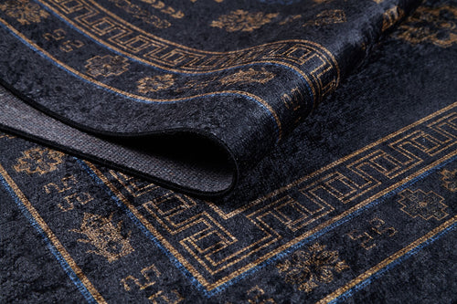 Load image 1 in gallery view. Close-up of the Ancient Legacy - Washable Rug - JR1890 (Custom Size) in dark blue and gold, featuring geometric and floral patterns. A folded corner reveals the rug's thickness and textured flat weave material.