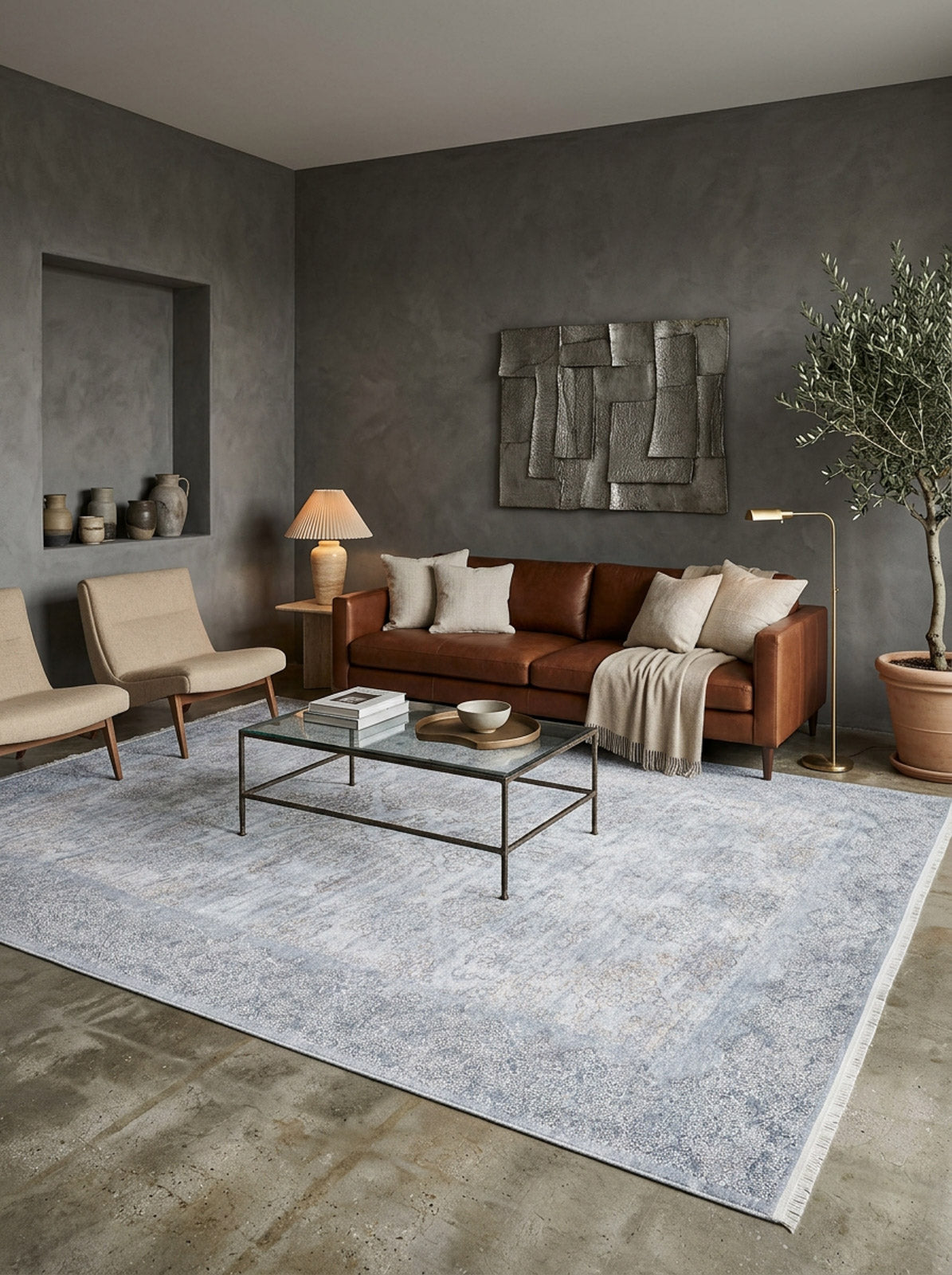 A modern living room featuring a brown leather sofa, beige chairs, glass coffee table, the Ancient Treasure - Washable Rug - JR1785 for high-traffic areas, plus a floor lamp, table lamp, abstract wall art, and a potted tree in the corner.