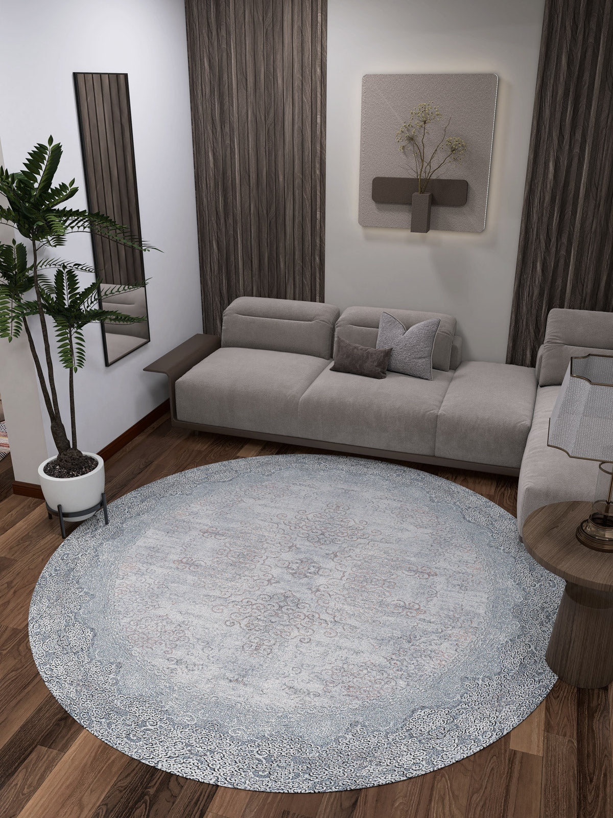 A modern living room features a gray sectional sofa, wood floors, a potted plant, wall art, a vertical mirror, and neutral decor. The centerpiece is the Ancient Treasure - Washable Rug - JR1785, ideal for high-traffic areas and contemporary design.