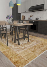 A modern kitchen with gray cabinets, black appliances, a dining table for four, purple flowers in a vase, and the Antique Insignia - Washable Rug - JR309—ideal for high-traffic areas—on the wooden floor. Two blue pendant lights hang above the table.