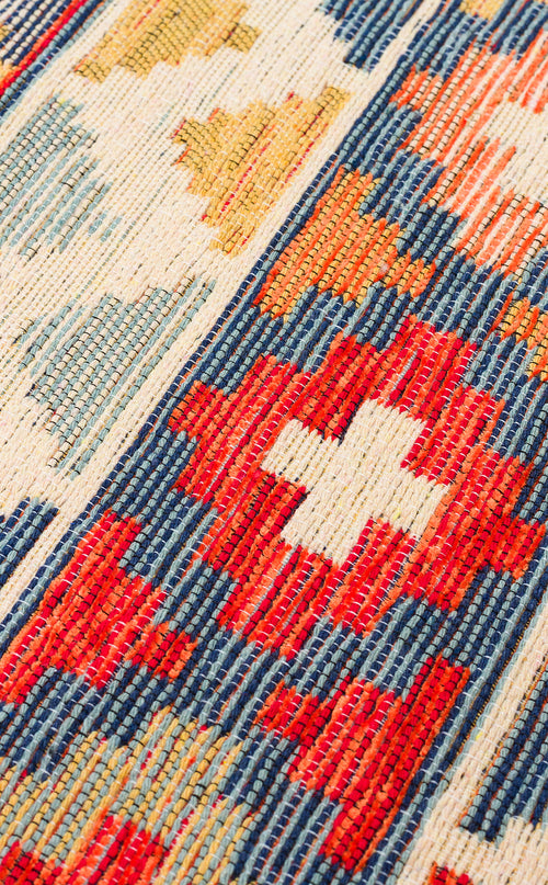 Load image 1 in gallery view. Close-up of the Aqua Flow - Washable Reversible Kilim (NMD02), featuring a vibrant folk-inspired Southwestern pattern with red, blue, yellow, and white geometric shapes and stripes.