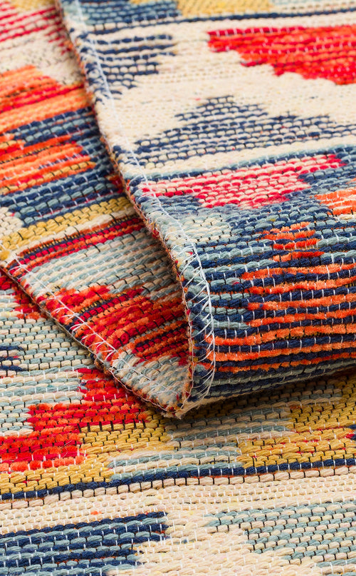 Load image 1 in gallery view. A detailed view of the Aqua Flow - Washable Reversible Kilim - NMD02 shows its vibrant red, blue, yellow, and cream patterns. The folded corner highlights the textured weave and striking geometric designs of this unique area rug.