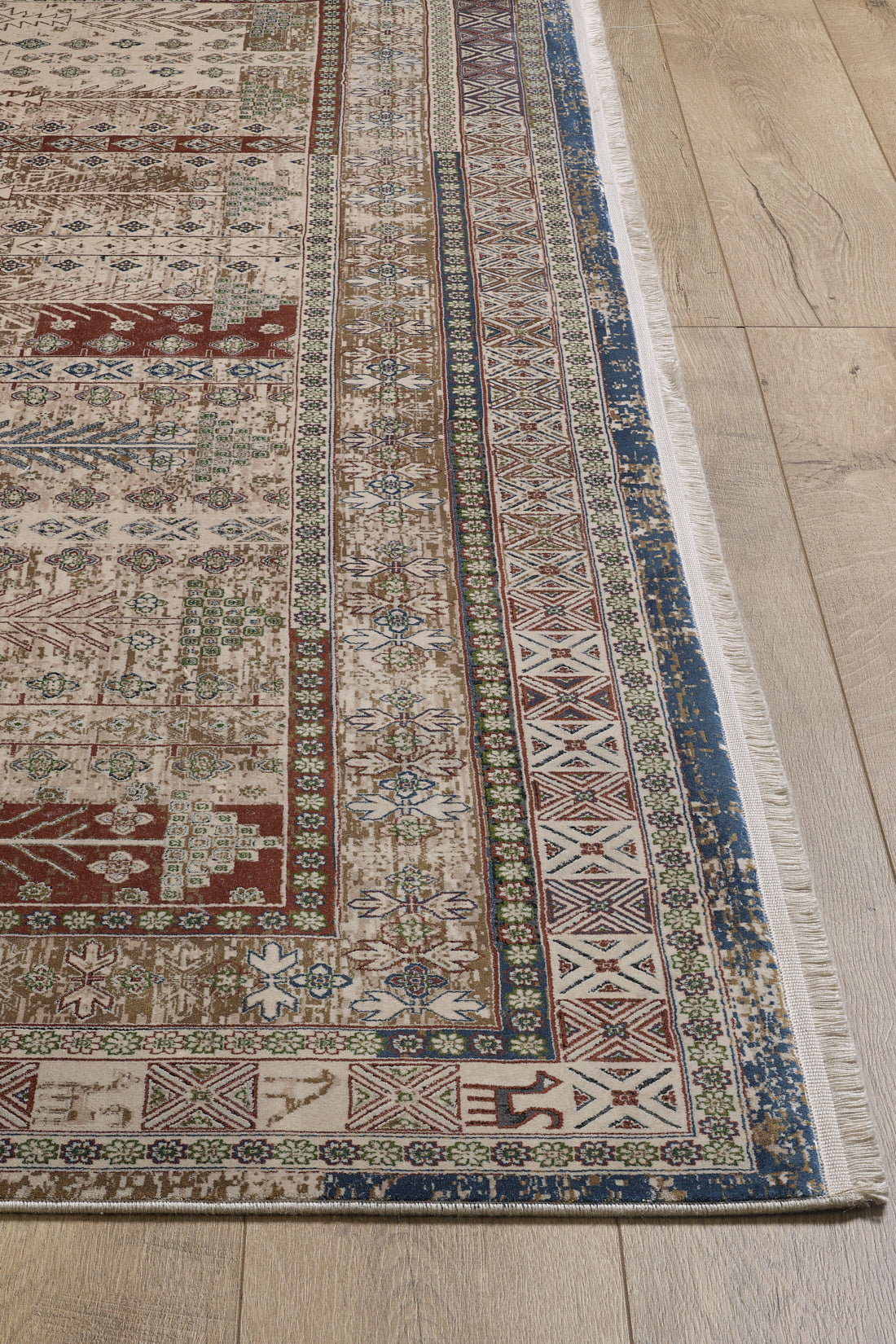 A detailed view of the Archery Elegance Premium Rug - Earthy - 2183B, a machine-made piece with intricate geometric and floral patterns in red, blue, green, and beige, plus decorative borders, placed on a light wood floor.