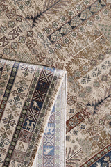 A close-up of the Archery Elegance Premium Rug - Earthy - 2183B shows its beige and brown geometric and floral patterns, with one corner folded to reveal the intricately detailed reverse side.