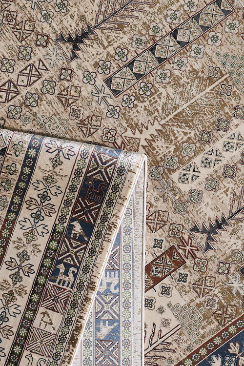 Bild 1 in Galerieansicht laden. A close-up of the Archery Elegance Premium Rug - Earthy - 2183B shows its beige and brown geometric and floral patterns, with one corner folded to reveal the intricately detailed reverse side.