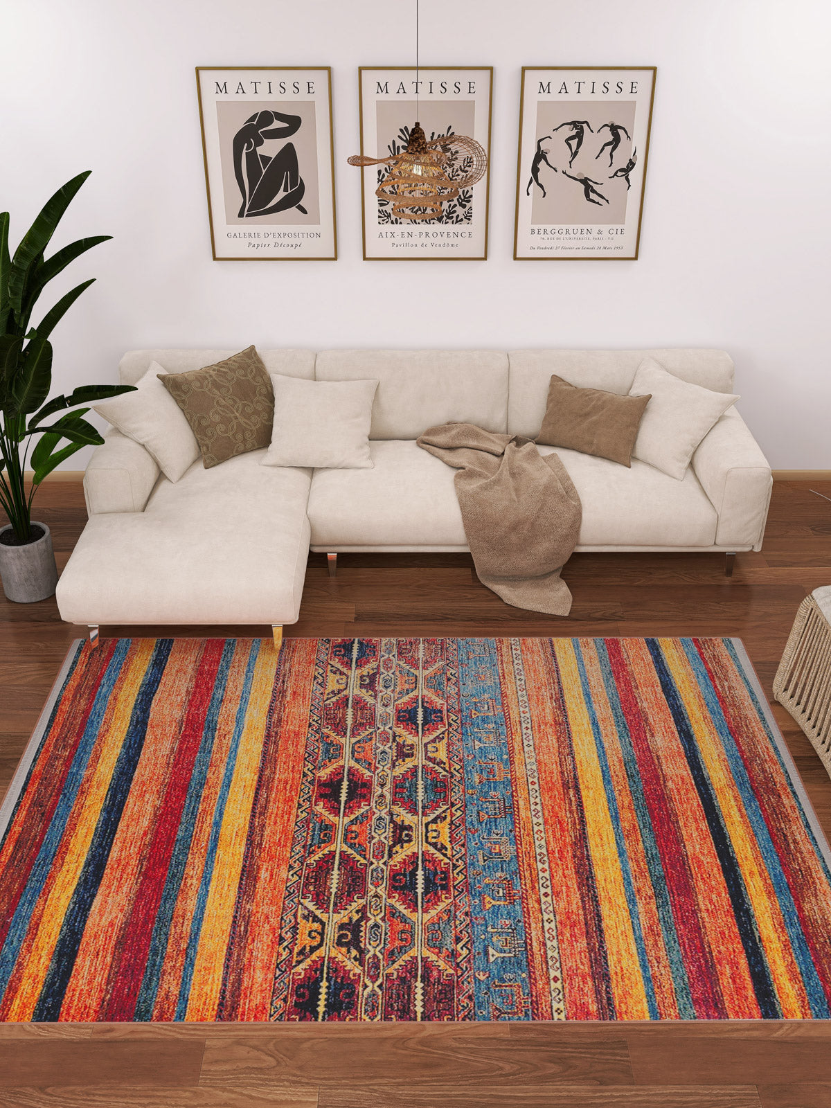 A modern living room with a white L-shaped sofa, brown cushions, beige throw, green plant, and three framed Matisse prints features the Arctic Chill - Washable Rug - JR860—a multicolor rug perfect for any high-traffic area.