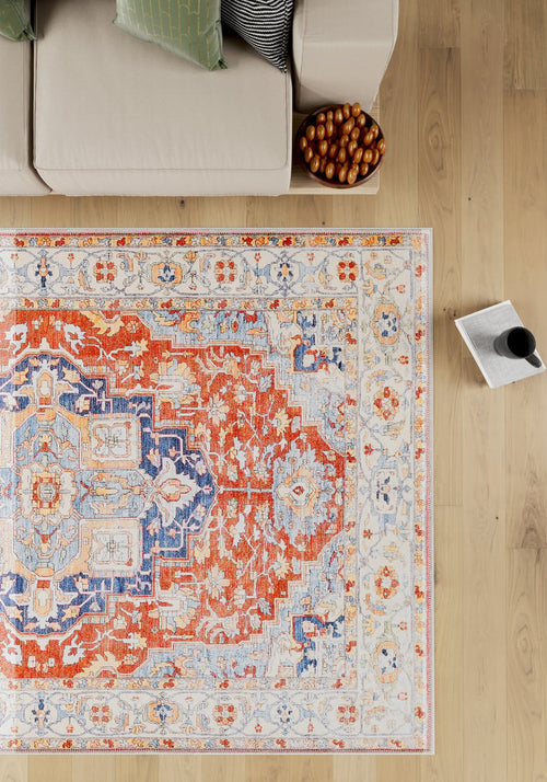 Load image 1 in gallery view. A beige sofa with striped cushions sits next to the Ardentis Medallion Washable Rug - LCC3002 (Outlet) US on a light wooden floor, with a bowl of snacks and a magazine beside a mug nearby.