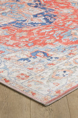 A close-up of the Ardentis Medallion Washable Rug - LCC3002 (Outlet) US reveals its intricate red, blue, and cream patterns and textured flat weave, displayed on a wooden floor with a detailed corner view.