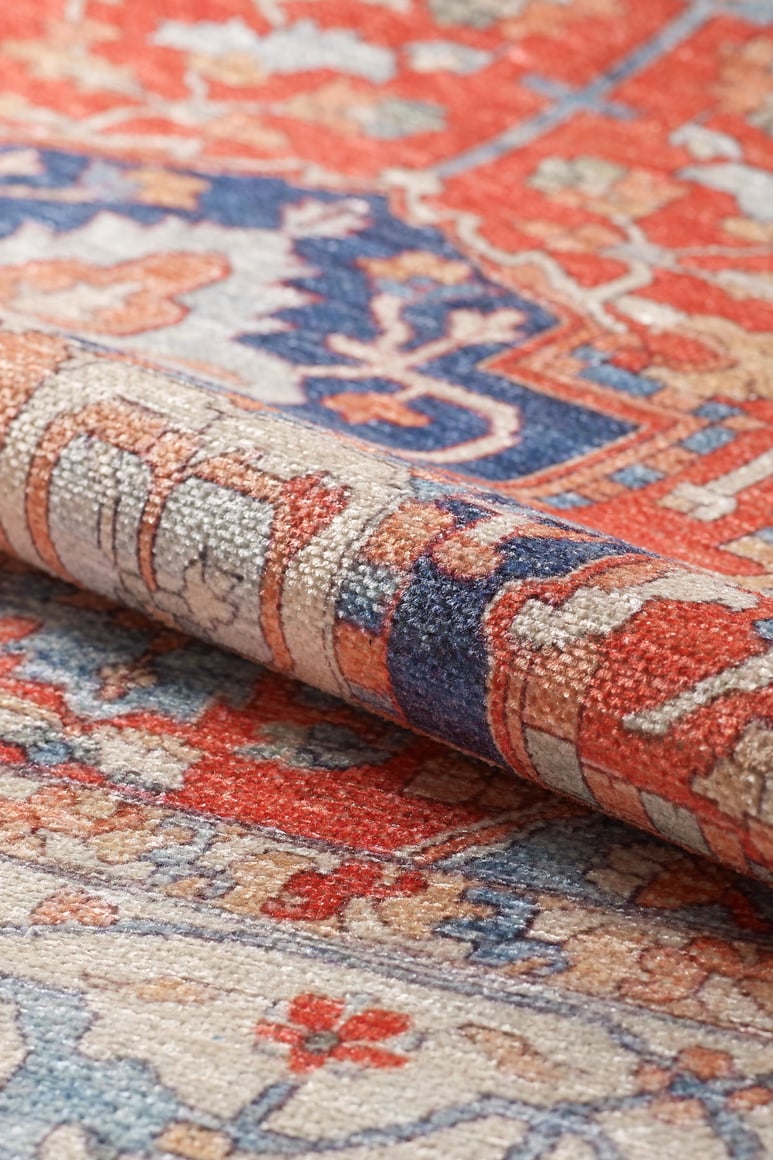 Close-up of a rolled corner of the Ardentis Medallion Washable Rug - LCC3002 (Custom Size), showing intricate red, blue, beige, and cream floral and geometric designs.