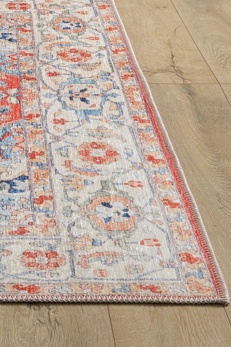 A close-up of the Ardentis Medallion Washable Rug - LCC3002 (Custom Size) featuring intricate floral and geometric patterns in red, blue, cream, and orange on a light wood floor.