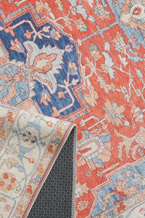 Bild 1 in Galerieansicht laden. A close-up of the Ardentis Medallion Washable Rug - LCC3002 (Custom Size) highlights its colorful floral and geometric designs in red, blue, and cream. One corner is slightly folded to reveal the backing underneath.