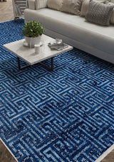 A close-up of a living room with a white sofa, gray and white pillows, a marble coffee table, and the Art Deco Elegance - Washable Rug - JR1224 in blue geometric patterns—ideal for high-traffic wooden floors.