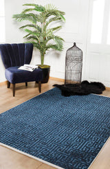 A modern room features the Art Deco Elegance - Washable Rug - JR1224 (Custom Size), a navy velvet chair with a book and glasses, a potted plant, black faux fur rug, and empty birdcage—ideal for high-traffic areas.