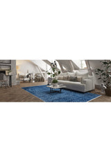 A modern loft living room with a white sofa, neutral pillows, a glass coffee table, green potted plants, and the Art Deco Elegance - Washable Rug - JR1224 (Custom Size). Slanted ceiling beams and large windows create an airy vibe.