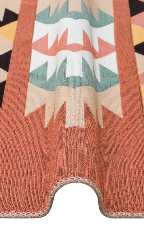 Load image 1 in gallery view. A close-up of the Artisan Mesh - Washable Double-Sided Kilims - AR39, a multicolour recycled cotton rug in orange, beige, black, green, and white geometric patterns, draped over a curve to showcase its texture and design.