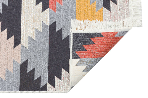 Load image 1 in gallery view. The Artisan Touch - Washable Double-Sided Kilims - AR20 features a reversible design with geometric zigzag patterns in gray, black, peach, yellow, and red, partially folded to reveal the underside and its white fringe.