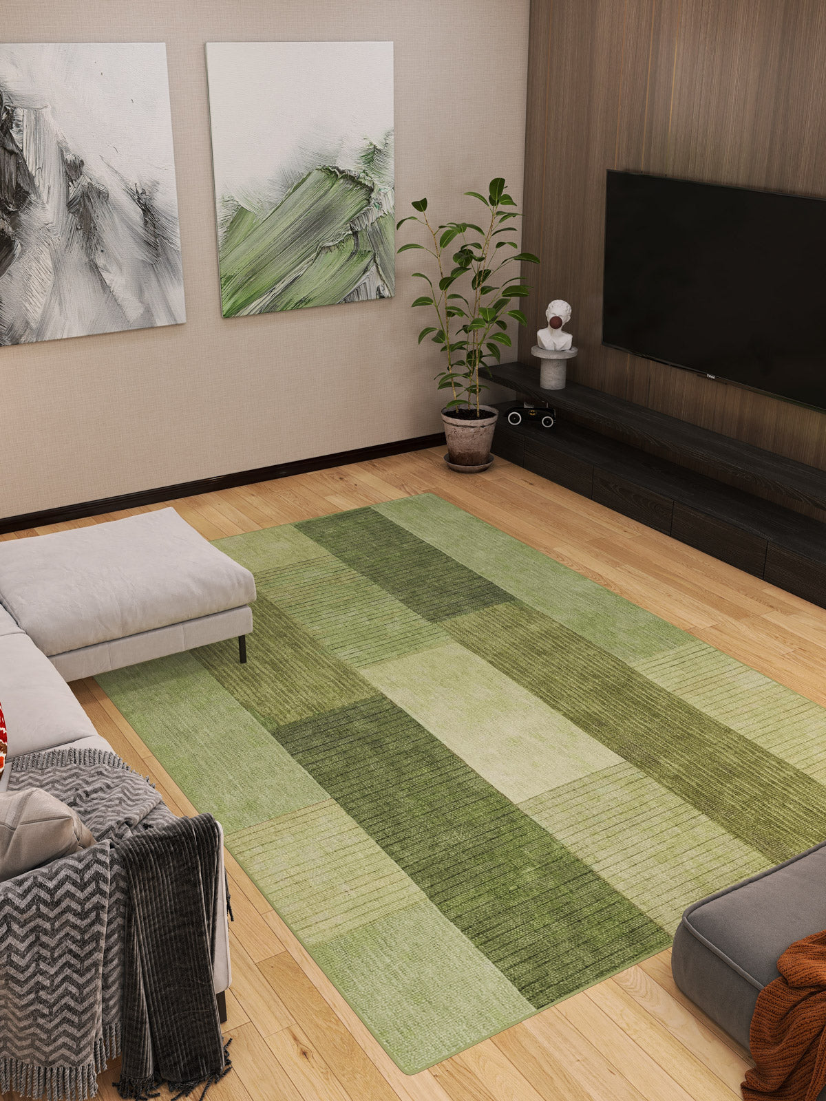 A modern living room featuring the Artisanal Essence - Washable Rug - JRN32 (Custom Size) in a green checkered pattern, light wood floors, a gray sectional sofa, abstract wall art, a potted plant, and a flat-screen TV on a dark wood console.