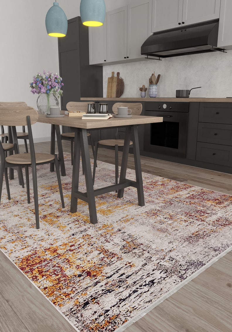 Modern kitchen and dining area with black cabinets, light wood furniture, a vase of purple flowers on the table, two blue pendant lights, and the Artistic Abstraction - Washable Rug - JR775 (Custom Size) in orange, yellow, and cream tones on the floor.