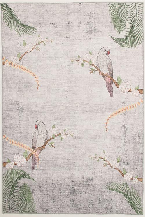 Bild 1 in Galerieansicht laden. The Ashwing Silence - Washable Rug (JR0048) features two gray parrots with pink faces on flowering branches, green palm leaves, and orange floral vines in the corners. Its light-colored background has a subtle, textured look.
