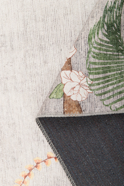 Bild 1 in Galerieansicht laden. A close-up of the Ashwing Silence - Washable Rug - JR0048 shows its tropical floral pattern with green leaves and white flowers, a plain dark underside, and a subtle light-colored weave in the background.