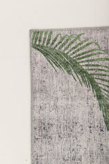A green palm leaf print accents the upper left corner of the Ashwing Silence - Washable Rug - JR0048, featuring a textured, light-colored surface set against a plain light background.