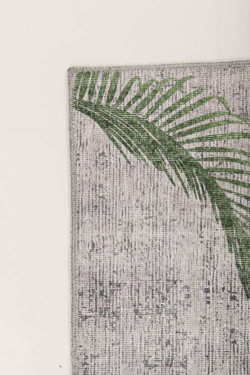 Bild 1 in Galerieansicht laden. A green palm leaf print accents the upper left corner of the Ashwing Silence - Washable Rug - JR0048, featuring a textured, light-colored surface set against a plain light background.