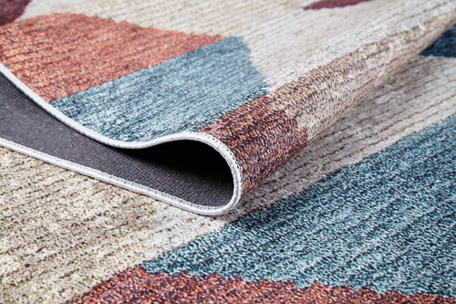 Load image 1 in gallery view. A close-up of the Asymmetrical Wonder - Washable Rug - JR1725 (Custom Size) featuring abstract blue, brown, and beige patterns with a corner curled to show the black underside—ideal for high-traffic areas.