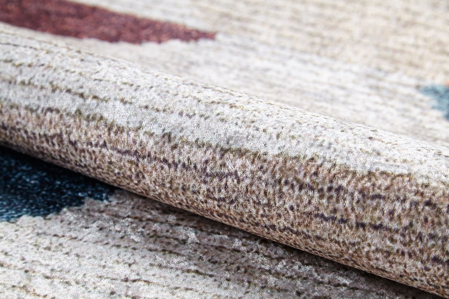 A close-up of the Asymmetrical Wonder - Washable Rug - JR1725 (Custom Size) shows its beige and brown textured surface with blue and red accents, soft fibers, and subtle patterns—perfect for high-traffic or allergy-sensitive spaces.