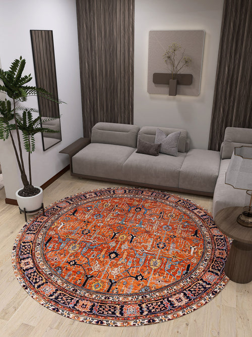 Bild 1 in Galerieansicht laden. A modern living room showcases the Aurelius Coral Washable Rug - LCC3005 (Custom Size), a round, vibrant orange rug ideal for high-traffic areas, paired with a gray sectional sofa, potted plant, side table, wall art, and wooden panels.