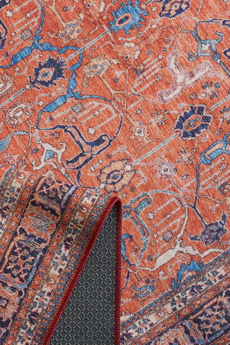 A close-up of the Aurelius Coral Washable Rug - LCC3005 (Custom Size) shows its intricate blue, pink, white, and orange patterns. One corner is folded to reveal the patterned underside and durable dark backing—ideal for high-traffic spaces.