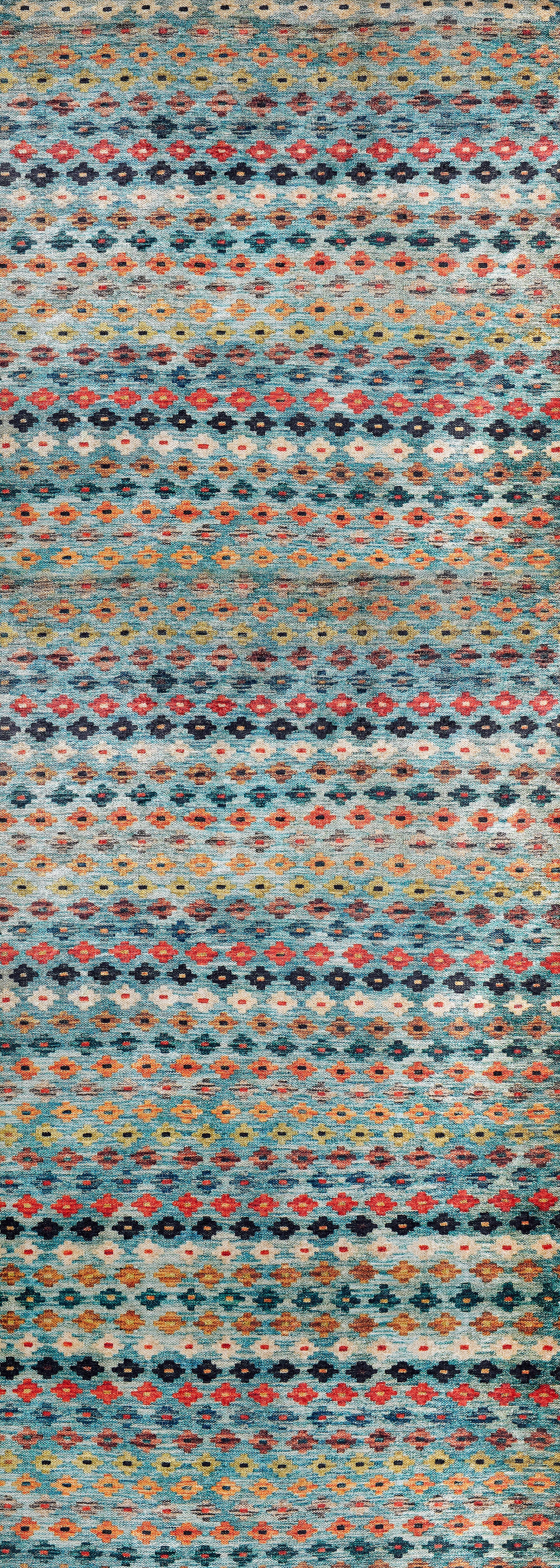 The Aztec Ambience Washable Rug (JR1086) features a repeating geometric pattern with horizontal rows of small ovals and diamonds in blue, orange, red, and brown—ideal as a multicolor rug for high-traffic areas.