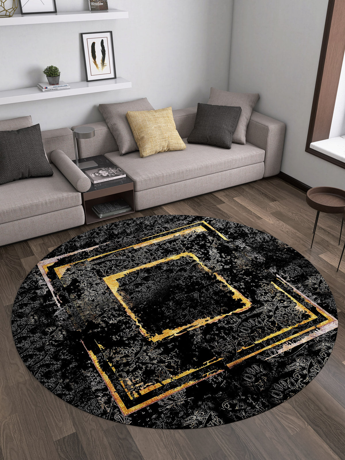 A modern living room with a gray sectional, yellow accent pillow, round table, and the Azure Glow - Washable Rug - JR1337 featuring abstract yellow and gold geometric patterns—stylish and ideal for high-traffic spaces on dark wood flooring.