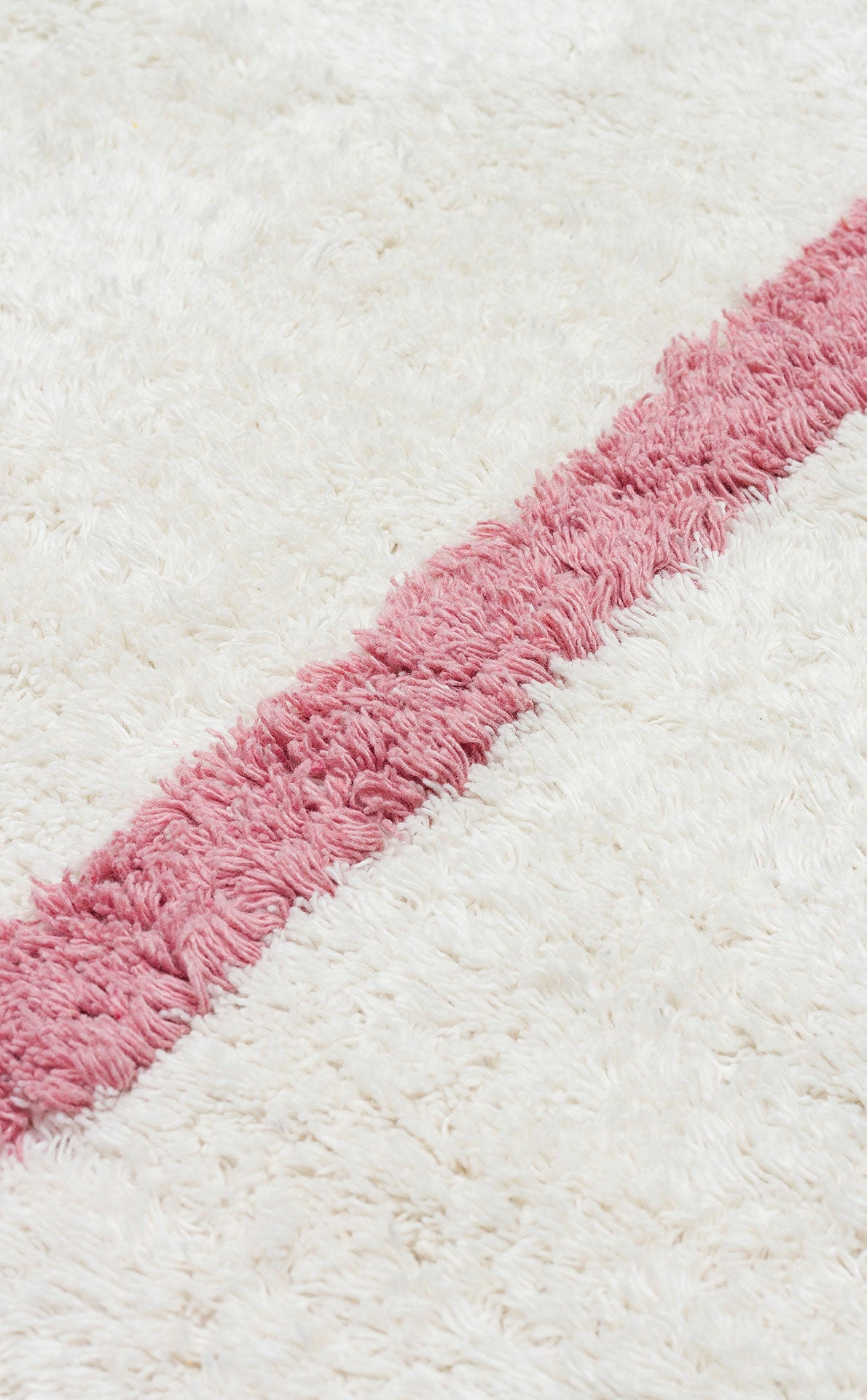 The Baby Breeze - Washable Shaggy - CBN01 is a white, fluffy, washable rug with a bold diagonal pink stripe—ideal as a cozy kids' room or nursery rug.