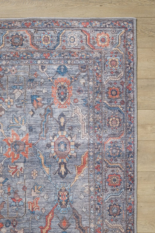 Load image 1 in gallery view. A corner of the Bellaris Gray Washable Rug - LCC3003 (Outlet) US, featuring intricate geometric and floral patterns in blue, gray, red, and orange, is shown laid on light wood flooring.