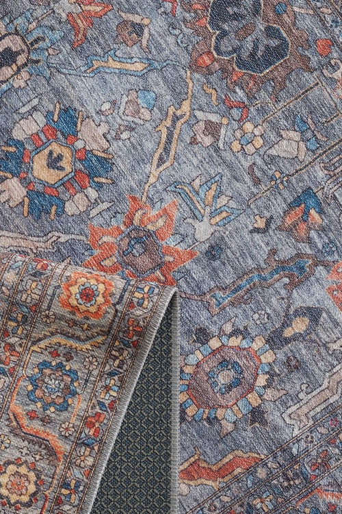 Load image 1 in gallery view. A close-up of the Bellaris Gray Washable Rug - LCC3003 (Outlet) US shows a blue-gray background with intricate floral and geometric patterns, plus a folded corner revealing its textured dark blue and gray lattice underside.
