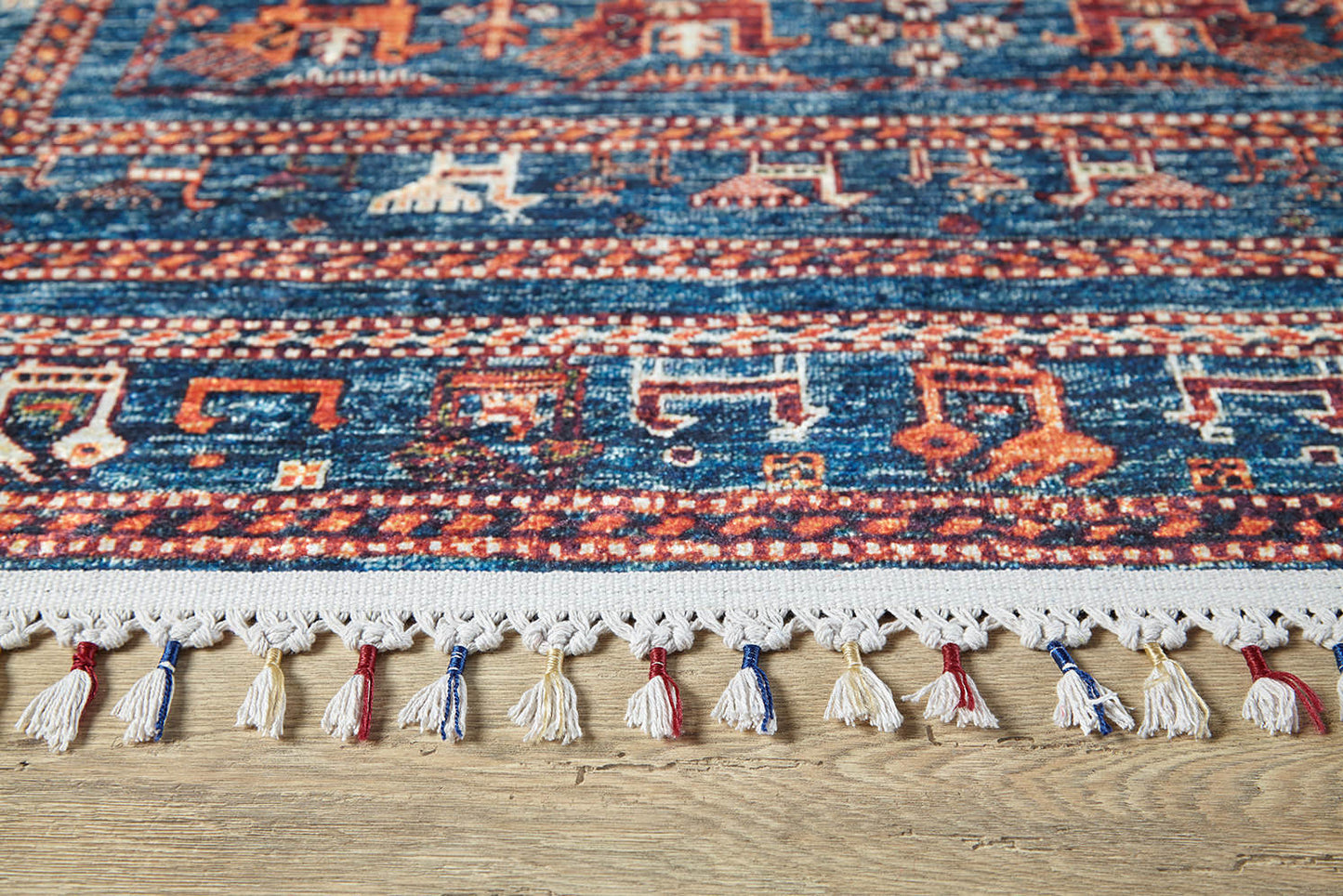 A close-up of the Berber Beauty - Washable Rug - JR5092 (Custom Size) in blue with geometric patterns and a white fringe, displayed on a wooden floor—ideal for high-traffic areas.
