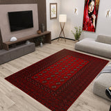 A modern living room showcases the Berry Pattern - Kilim - BHR04 rug, light wooden floors, a gray sofa, TV on a wood-paneled wall, floor lamp, potted plants, and a vibrant portrait of a woman