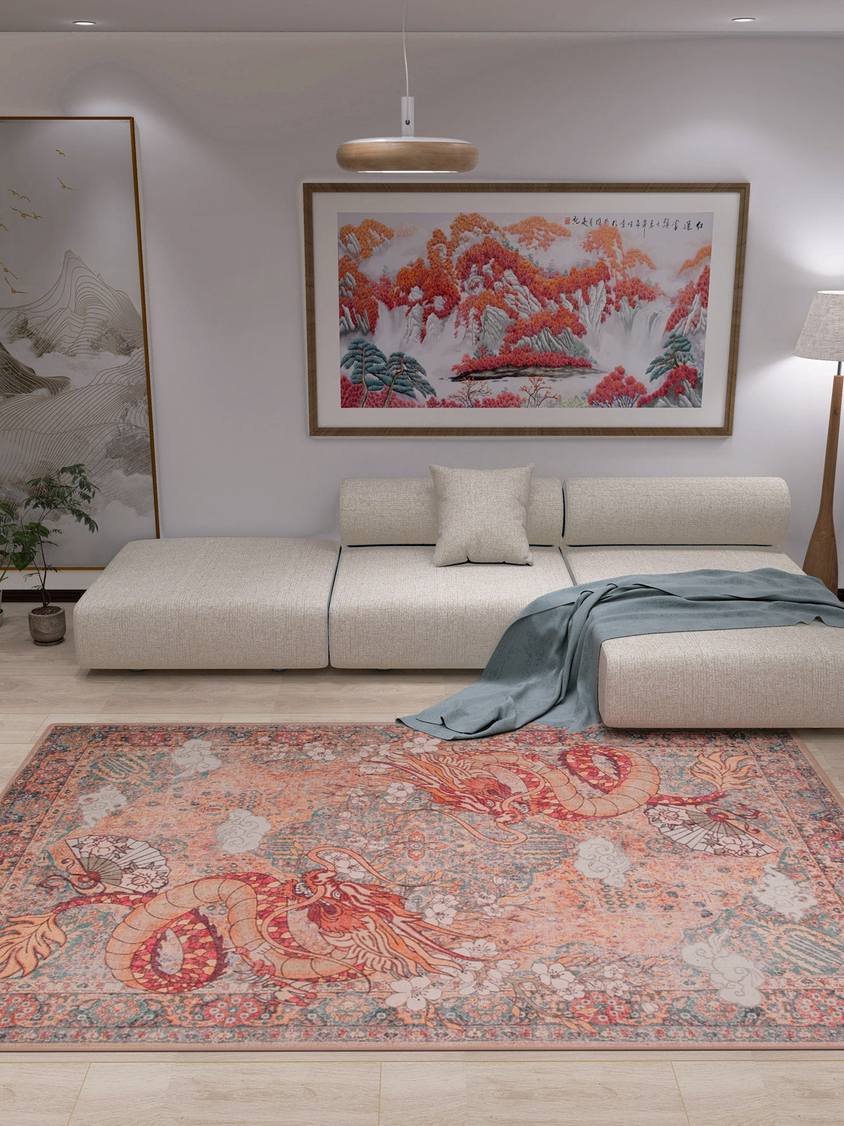 A modern living room with a beige sectional sofa, gray throw blanket, and the Blazefang Myth Washable Rug (JR0049) in red with a subtle geometric pattern. White walls feature a large landscape painting and tall floor lamp; a plant sits by the sofa.