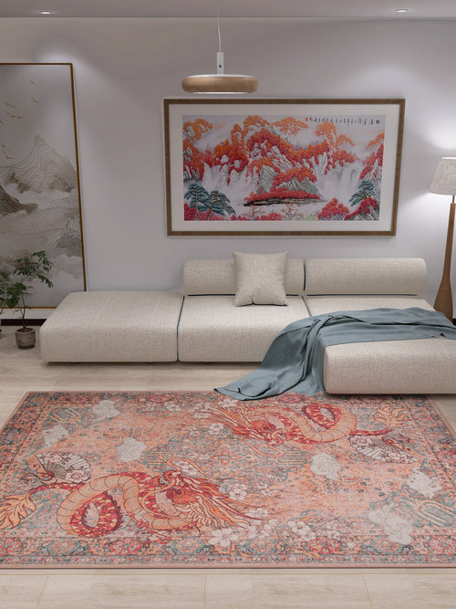 Load image 1 in gallery view. A modern living room with a beige sectional sofa, gray throw blanket, and the Blazefang Myth Washable Rug (JR0049) in red with a subtle geometric pattern. White walls feature a large landscape painting and tall floor lamp; a plant sits by the sofa.