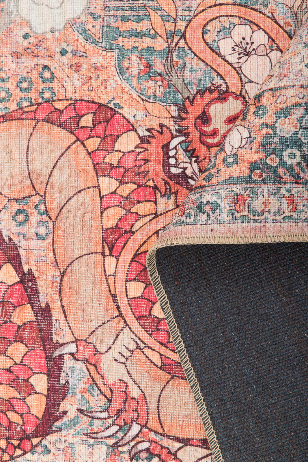 A close-up of the Blazefang Myth - Washable Rug - JR0049 shows its vivid dragon design in red, orange, and beige. One corner is flipped to display the dark blue underside and stitched edge.