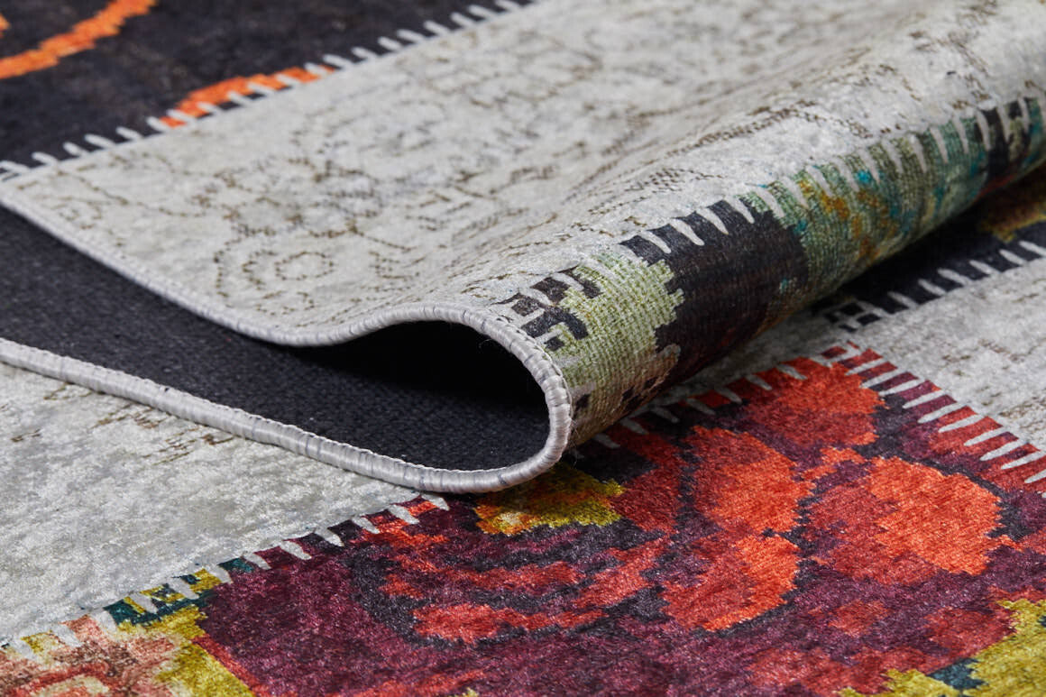 A close-up of the Blooming Paradise - Washable Rug - JR188 (Custom Size) shows its folded corner, stitched edges, and red, orange, green, and gray floral and abstract designs—ideal for adding style to high-traffic areas.