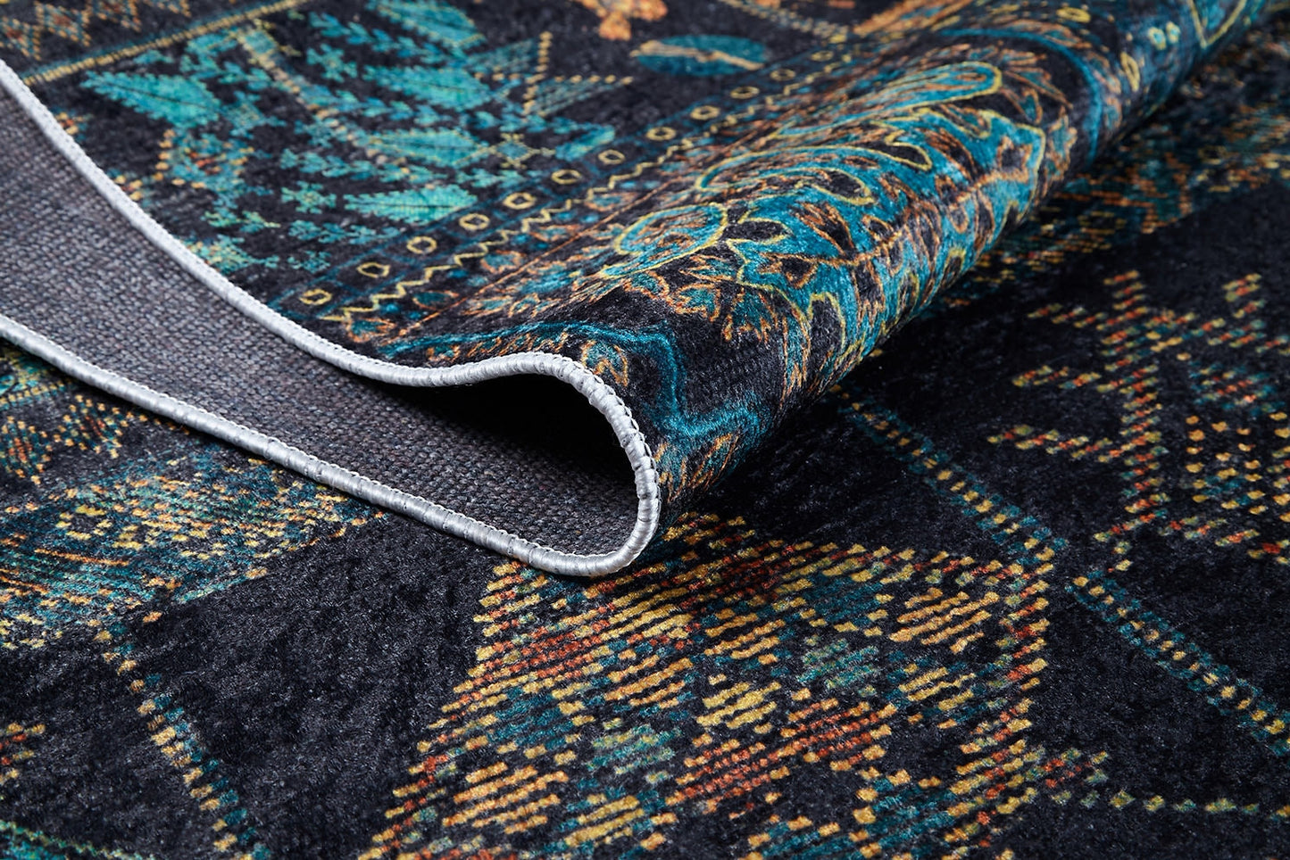 A close-up of the Blossoming Bazaar - Washable Rug - JR1862 (Custom Size) shows its dark, teal, gold, and brown patterns. A folded corner reveals the detailed front and textured underside—perfect for high-traffic spaces.