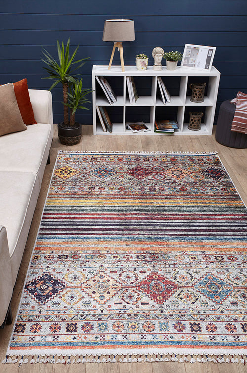 Load image 1 in gallery view. A modern living room features the Bohemian Bouquet - Washable Rug - JR5090 (Custom Size), a beige sofa with cushions, potted plant, white cube bookshelf with decor and books, and a table lamp set against a navy blue wall.