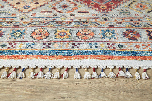 Load image 1 in gallery view. A close-up of the Bohemian Bouquet - Washable Rug - JR5090 (Custom Size), featuring intricate geometric and floral patterns with white fringe tassels, displayed on a light wooden floor.