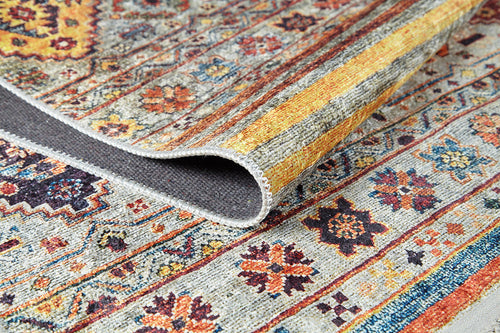 Load image 1 in gallery view. A close-up of the Bohemian Bouquet - Washable Rug - JR5090 (Custom Size) shows vibrant floral and geometric patterns in yellow, orange, blue, and red on gray, with a folded corner highlighting its easy-care flat weave design.