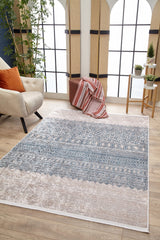 A modern living room features the Bohemian Nights - Washable Rug - JR1585 (Custom Size), ideal for high-traffic areas, a cream armchair with orange pillows, a brown pouf with a striped blanket, potted plants, and bright arched windows.