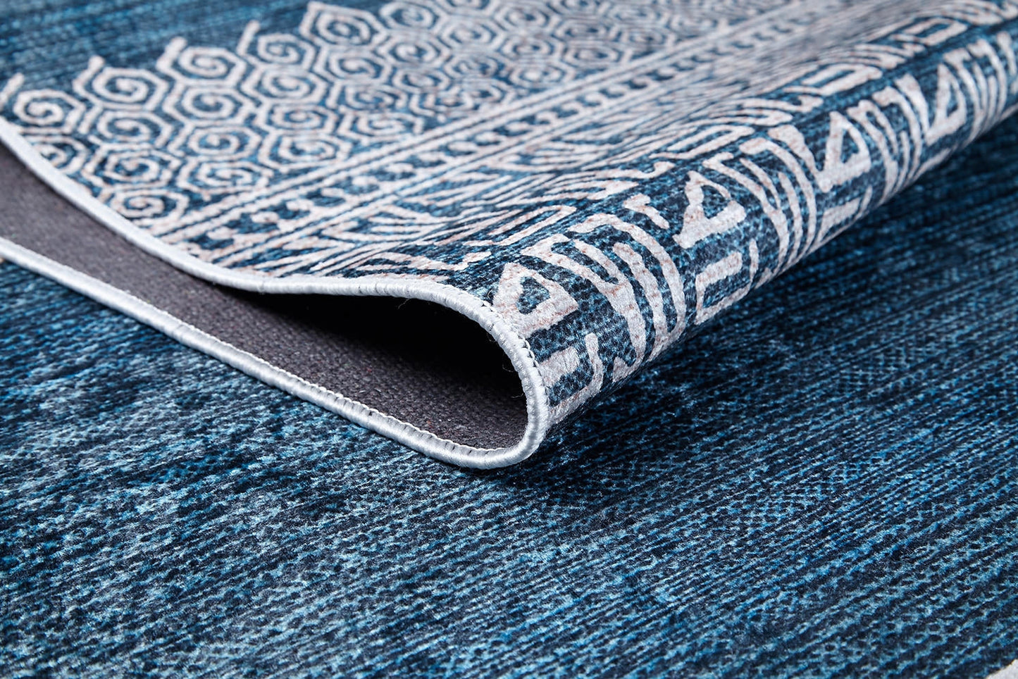 A close-up of the Bohemian Retreat - Washable Rug - JR1589 (Custom Size), showing its blue and white geometric patterns and textured underside. This washable rug is ideal for high-traffic areas with its intricate decorative designs.