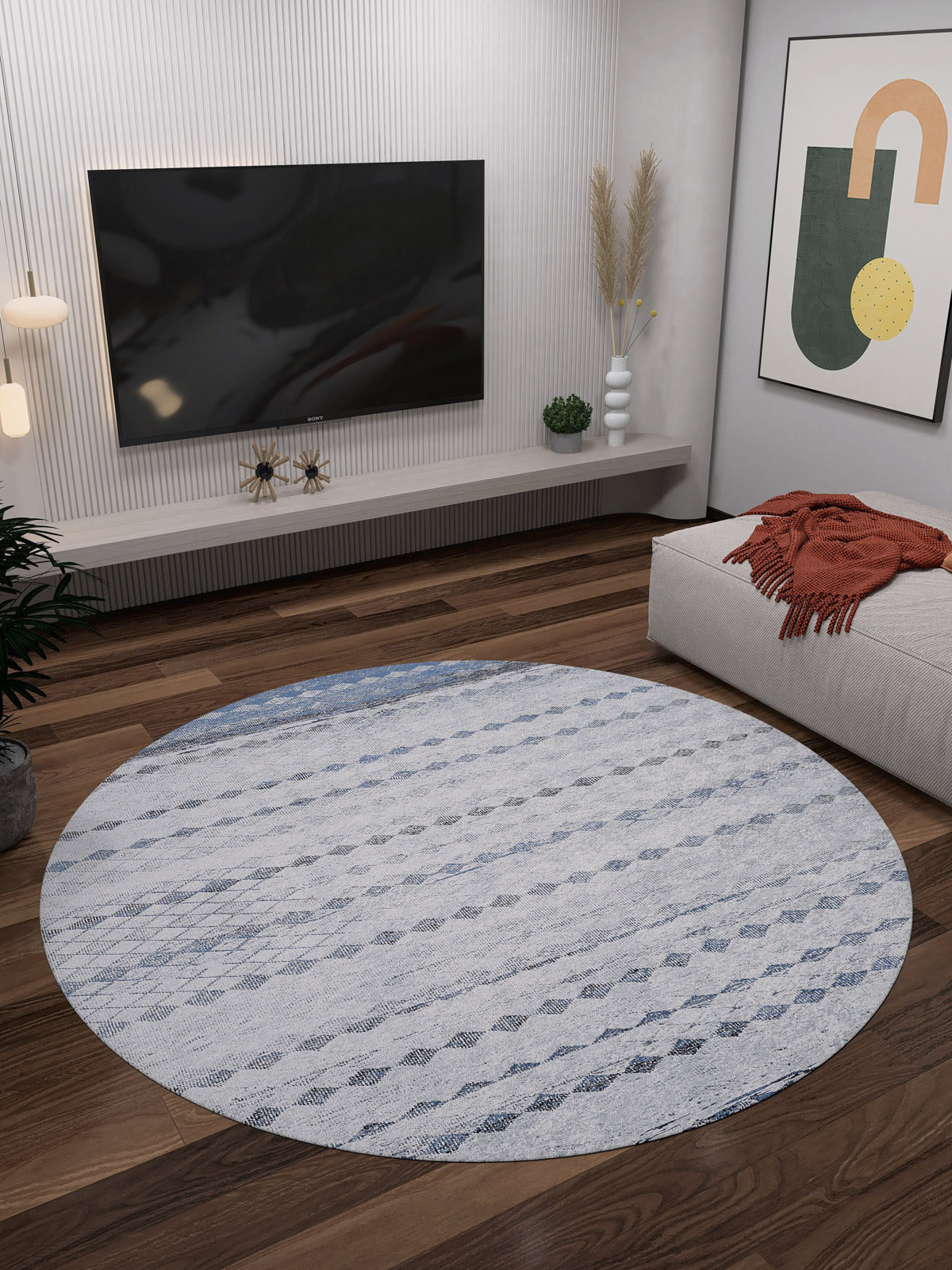 A modern living room with the Bohemian Reverie - Washable Rug - JR1974 in gray-anthracite on wooden floors, a wall-mounted TV, abstract art, plants, and a beige couch with an orange throw—ideal for high-traffic areas.