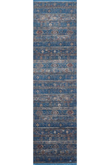 The Bohemian Tracery Rug - Blue - 2221B is a narrow, rectangular machine-made rug with a distressed blue background and intricate beige, brown, and ivory geometric and floral patterns in horizontal stripes.