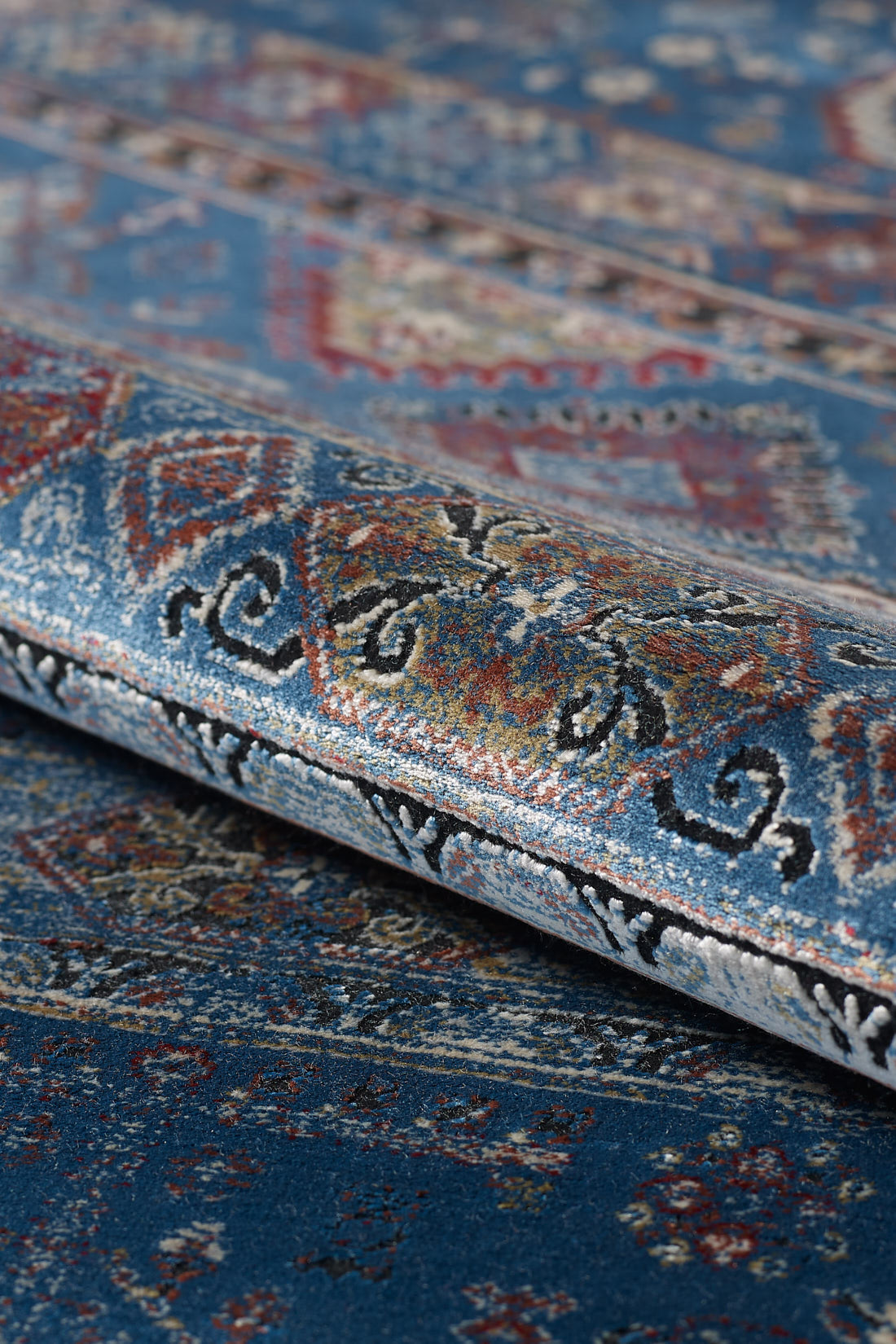 A close-up of the Bohemian Tracery Rug - Blue - 2221B displays its intricate multicolored designs, rolled edge, and detailed decorative texture.